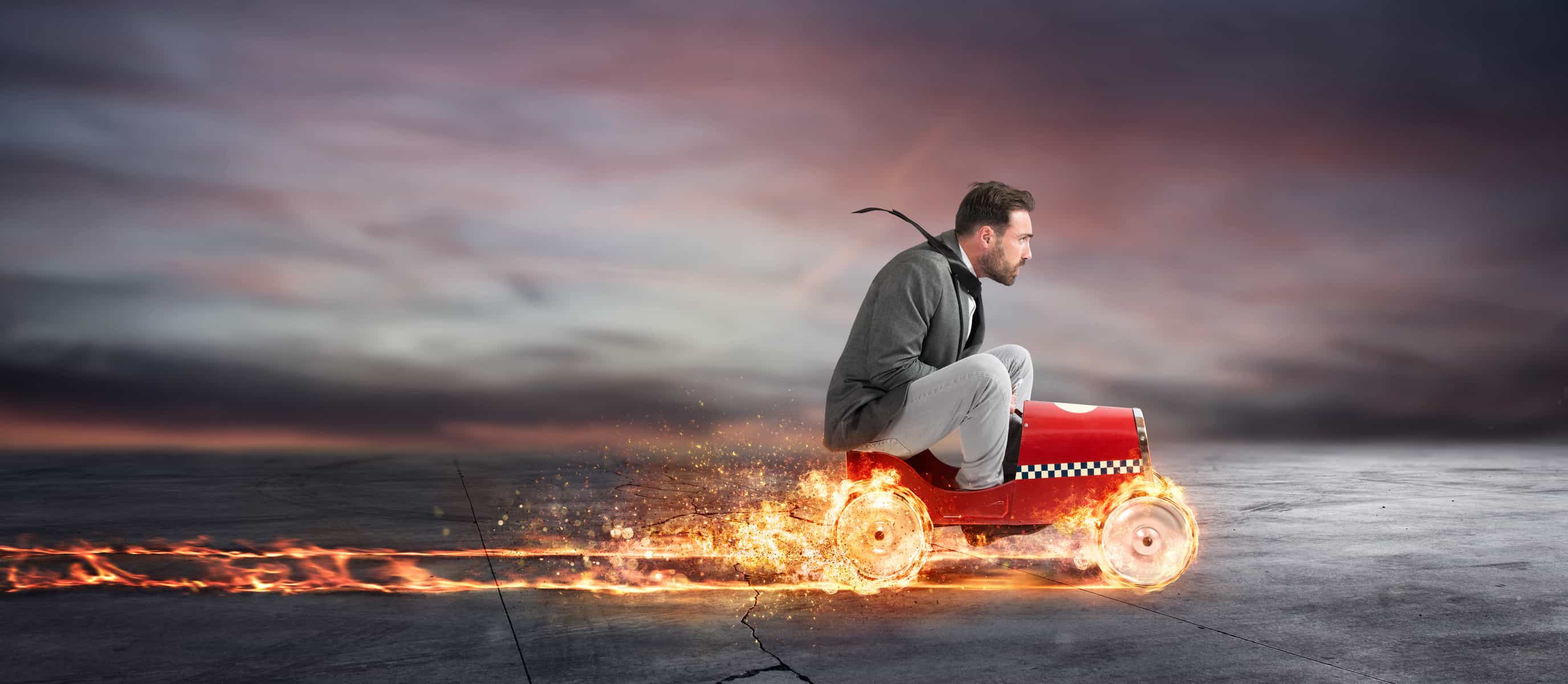 Man on a toy car going fast with the wheels creating flames